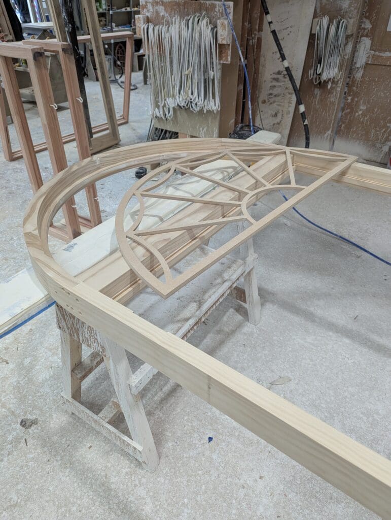 Intricately crafted timber window frame with decorative fretwork in Gowercroft Joinery's workshop, showcasing the use of Medite Tricoya for precise, durable detailing in curved heritage joinery
