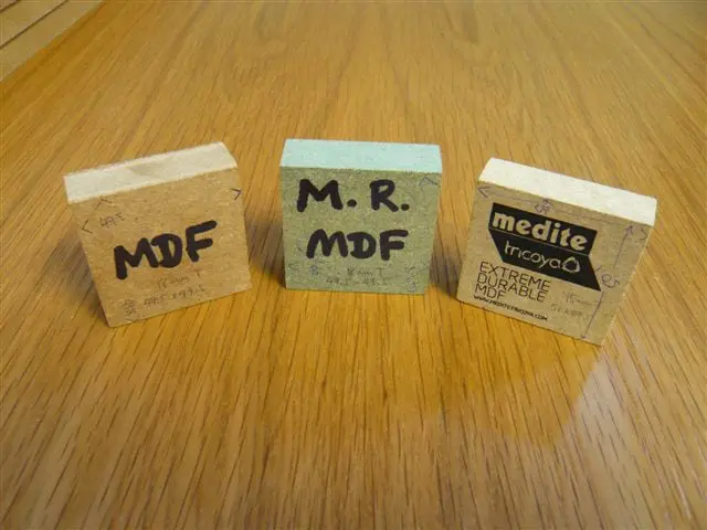 Three labelled MDF samples on a wooden surface, showing standard MDF, moisture-resistant MDF, and Medite Tricoya – a durable, weather-resistant MDF designed for extreme conditions.