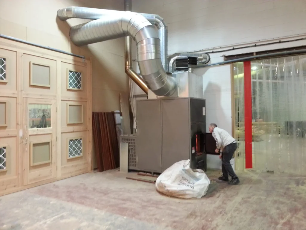 Gowercroft team member loading offcuts into a biomass heater in the workshop, showcasing the company’s commitment to sustainable joinery through efficient wood waste recycling and renewable heating.