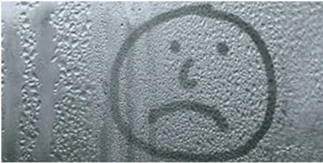 A sad face drawn on a window covered in condensation, illustrating the common issue of moisture build-up on glass.