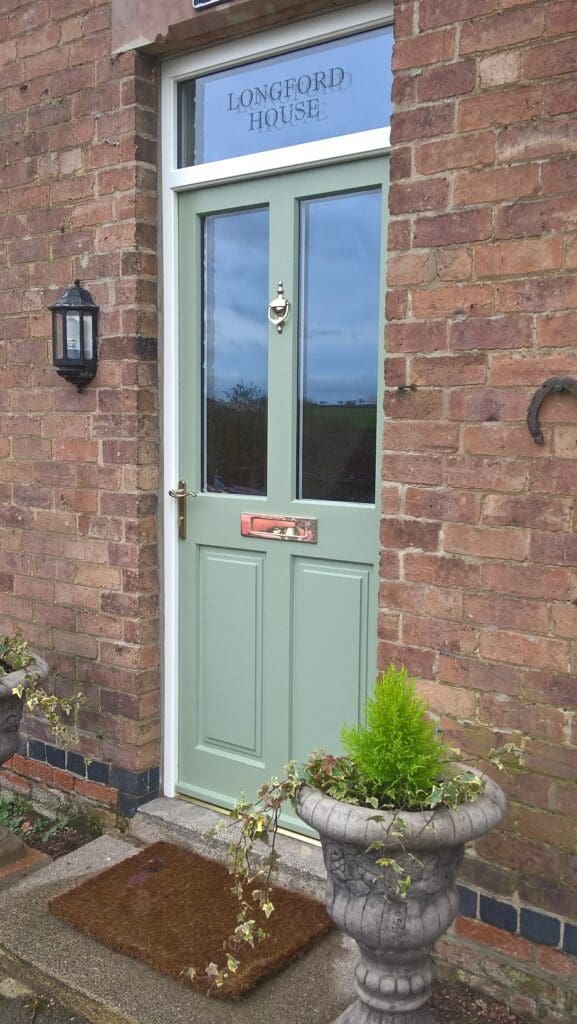 Timber front door painted sage green with a sign-written glazed fanlight reading “Longford House”, installed with matching frame and polished brass ironmongery.