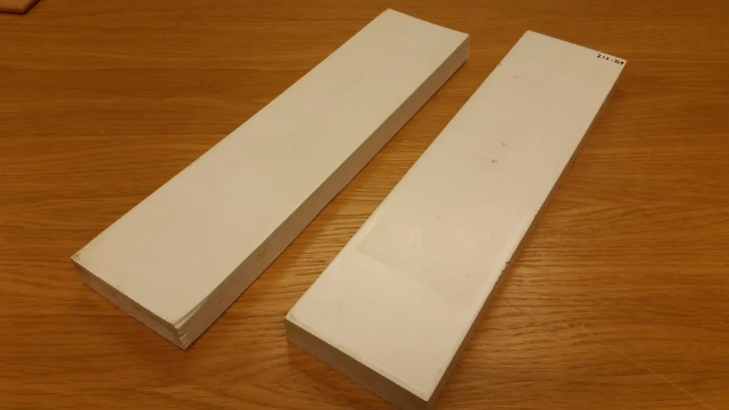 Two painted timber test samples used for QUV testing sit on a wooden table, showing minimal surface erosion and sheen loss after accelerated weathering cycles designed to simulate 10–15 years of real-world exposure.