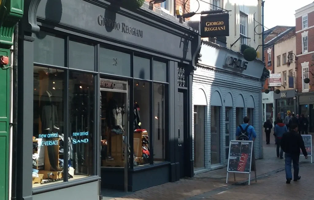 A stylish high street shopfront for Giorgio Reggiani in Derby, featuring elegant black timber-framed heritage windows that complement the traditional architecture of the building. The large display windows provide a refined, contemporary retail aesthetic while preserving the historical charm, illustrating the successful use of Gowercroft’s commercial heritage window solutions in a busy urban setting.
