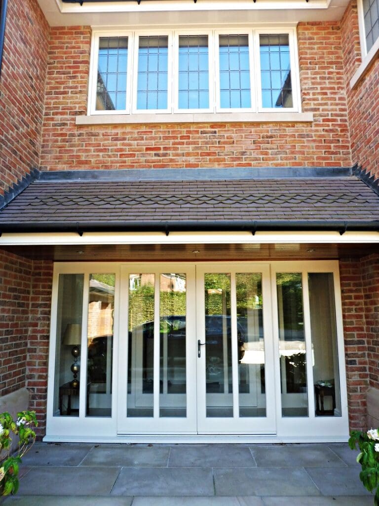 Five-panel Melbourne French doors with side lights and square leaded glazing, painted in Strutt yellow, set into a brick elevation.

