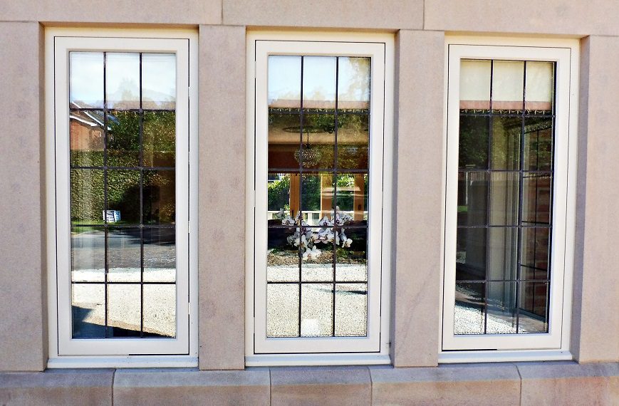 Three Hardwick casement windows with square leads and painted cream finish, fitted within stone mullions on the ground floor facade.