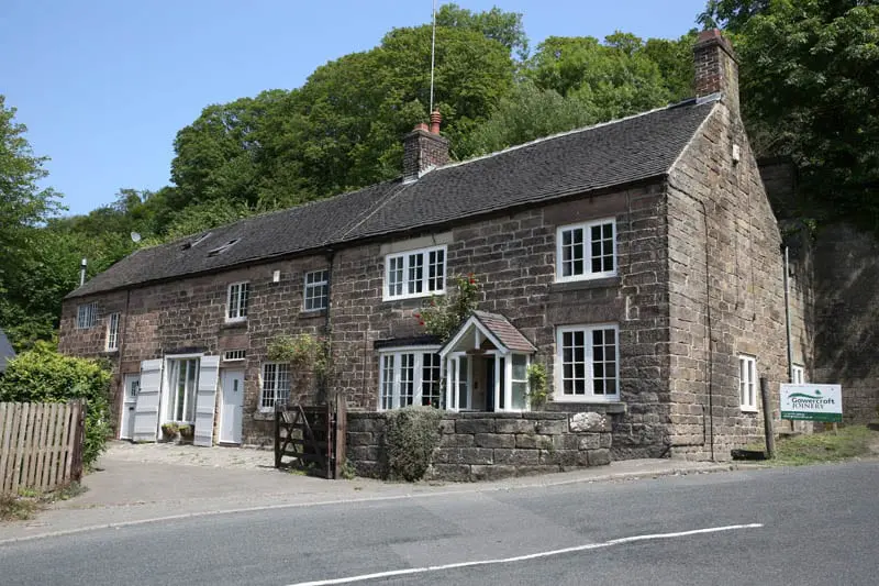 Front view of The Smithy in Whatstandwell, Derbyshire, showing Gowercroft’s heritage-style timber windows installed in a traditional stone cottage with a tiled roof and white porch.