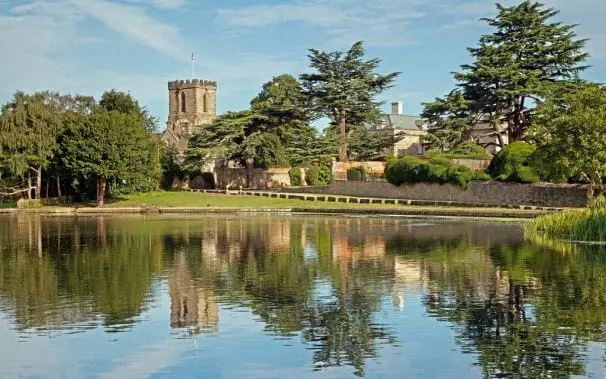 The church and green at Melbourne near derby with reflections in the mill pond