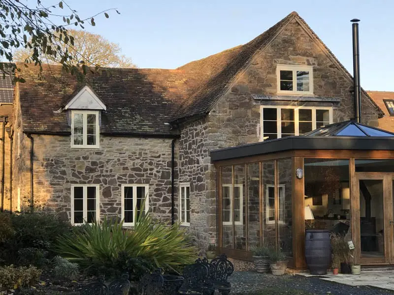 Rear elevation of the renovated Maltster’s Tap pub in Shropshire, featuring traditional flush casement timber windows by Gowercroft. A timber-framed garden room with glazed walls and a roof lantern forms a stylish extension that complements the original stone building.