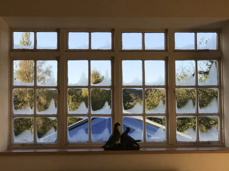 Before image of a heritage timber window showing severe condensation across all panes, highlighting poor insulation and the need for modern vacuum glazing to prevent heat loss and moisture build-up.