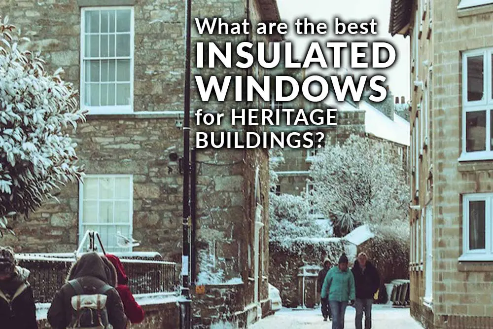 Snow-covered stone buildings with sash windows in a heritage street setting, overlaid with text reading “What are the best INSULATED WINDOWS for HERITAGE BUILDINGS?”.
