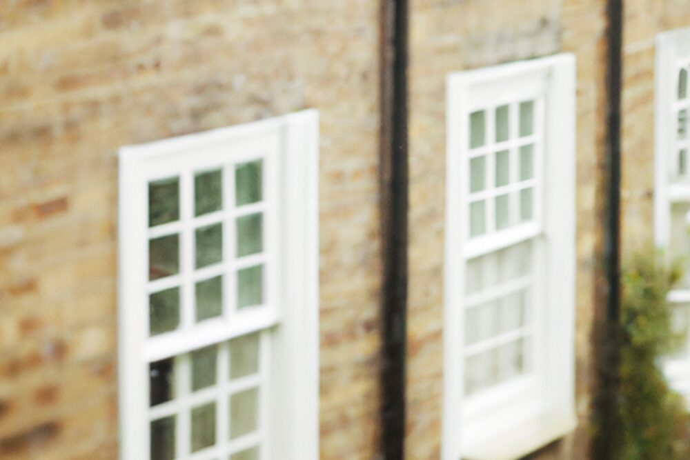 Close-up view of traditional white-painted sash windows on a brick façade of a historic building, illustrating heritage window design.