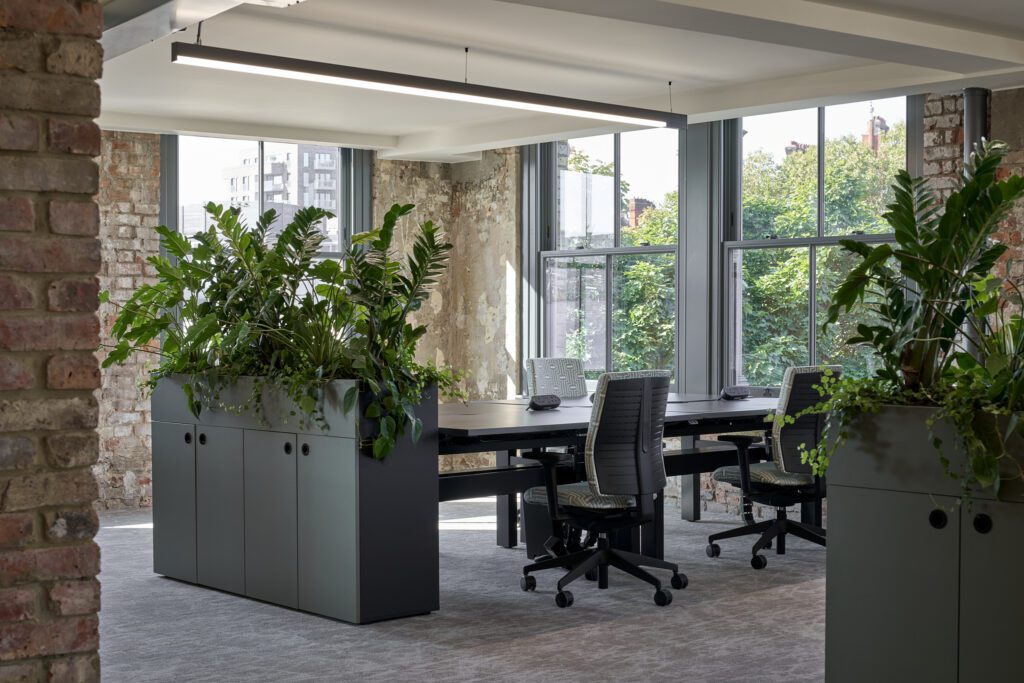Green workspace with large sash windows – The Waterman Building, Farringdon, London
An open-plan office filled with natural light from multiple large sash windows. Exposed brick walls and modern office furniture are complemented by lush greenery, adding warmth and vibrancy to the space.