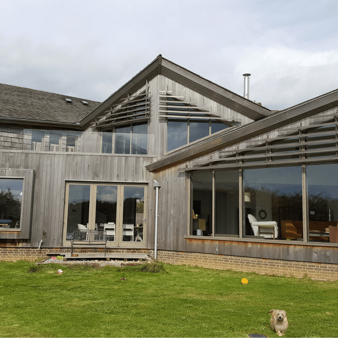 Contemporary timber-clad home with large timber performance tilt and turn windows and doors, creating expansive glazed openings onto the garden, blending modern design with natural materials.