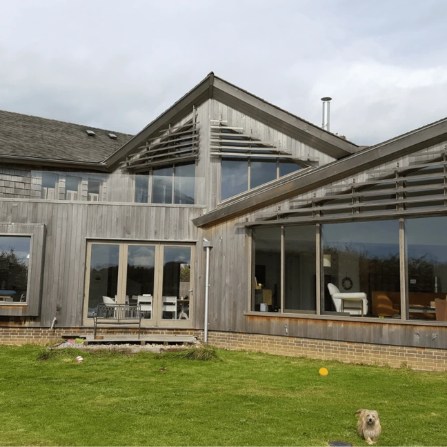 Contemporary timber-clad home with large timber performance tilt and turn windows and doors, creating expansive glazed openings onto the garden, blending modern design with natural materials.